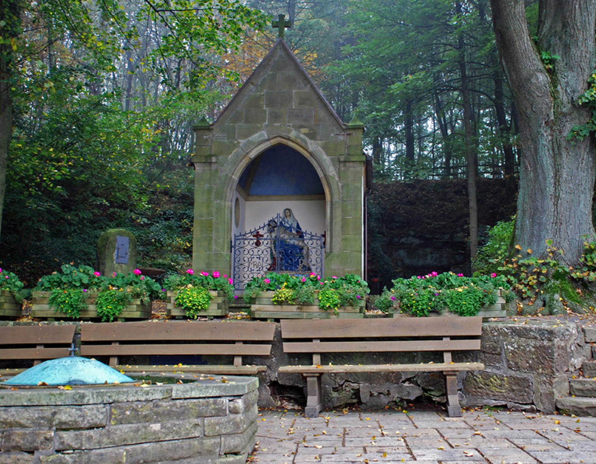 Die Brunnenkapelle im Wallfahrtsort Kleinenberg. Maria hält den Leichnam des vom Kreuz abgenommen Christus. Vor der Kapelle befindet sich der Mutter-Gottes-Brunnen. Bei diesem stehen drei Sitzbänke.