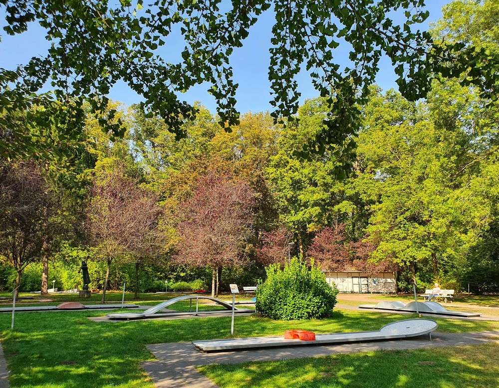 Blick auf die Bahnen der Minigolfanlage im Kurpark Bad Waldliesborn. Umgeben ist die Anlage von Bäumen.