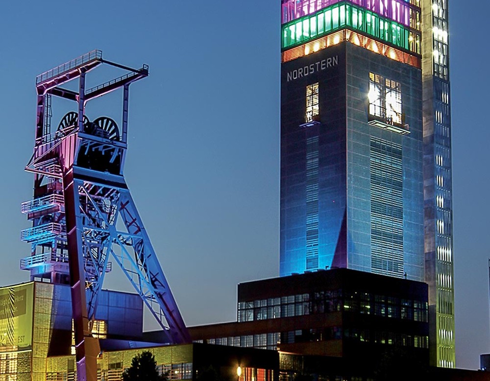 Der Nordsternturm der Zeche Nordstern ist in verschiedenen Farben beleuchtet.