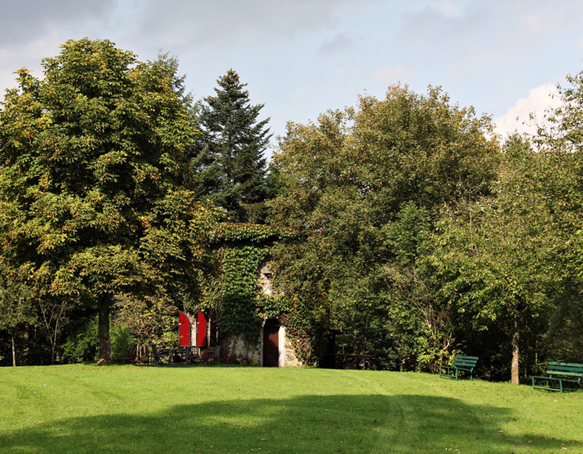 Wiese mit Bänken an der Burg Schnellenberg in Attendorn. Im Hintergrund kann man einen Teil der Burgmauer erkennen.