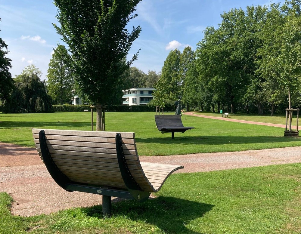 Zwei hölzerne Liegen im Kurpark. Sie laden zum Entspannen und zum Sonnetanken ein.