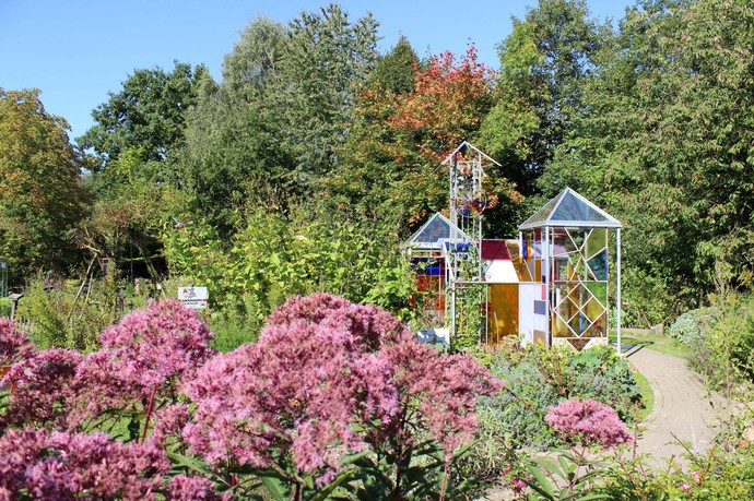 Blick auf den Schulgarten des Umweltzentrums Heerser Mühle. In dem Gewächshaus aus buntem Glas wachsen Kakteen.