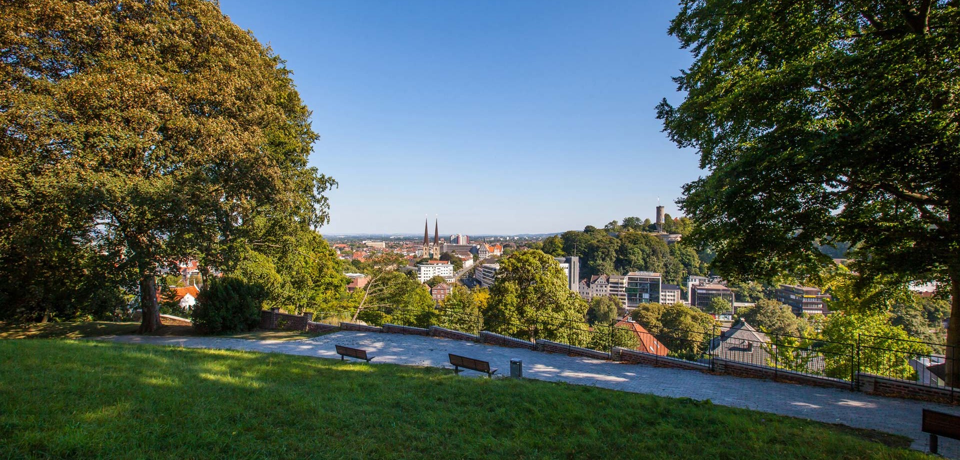 Panorama über den Süden Bielefelds von der Parkanlage Johannisberg. Neben dem Burgfried der Sparrenburg sieht man unter anderem auch die beiden Glockentürme der Neustädter Marienkirche.