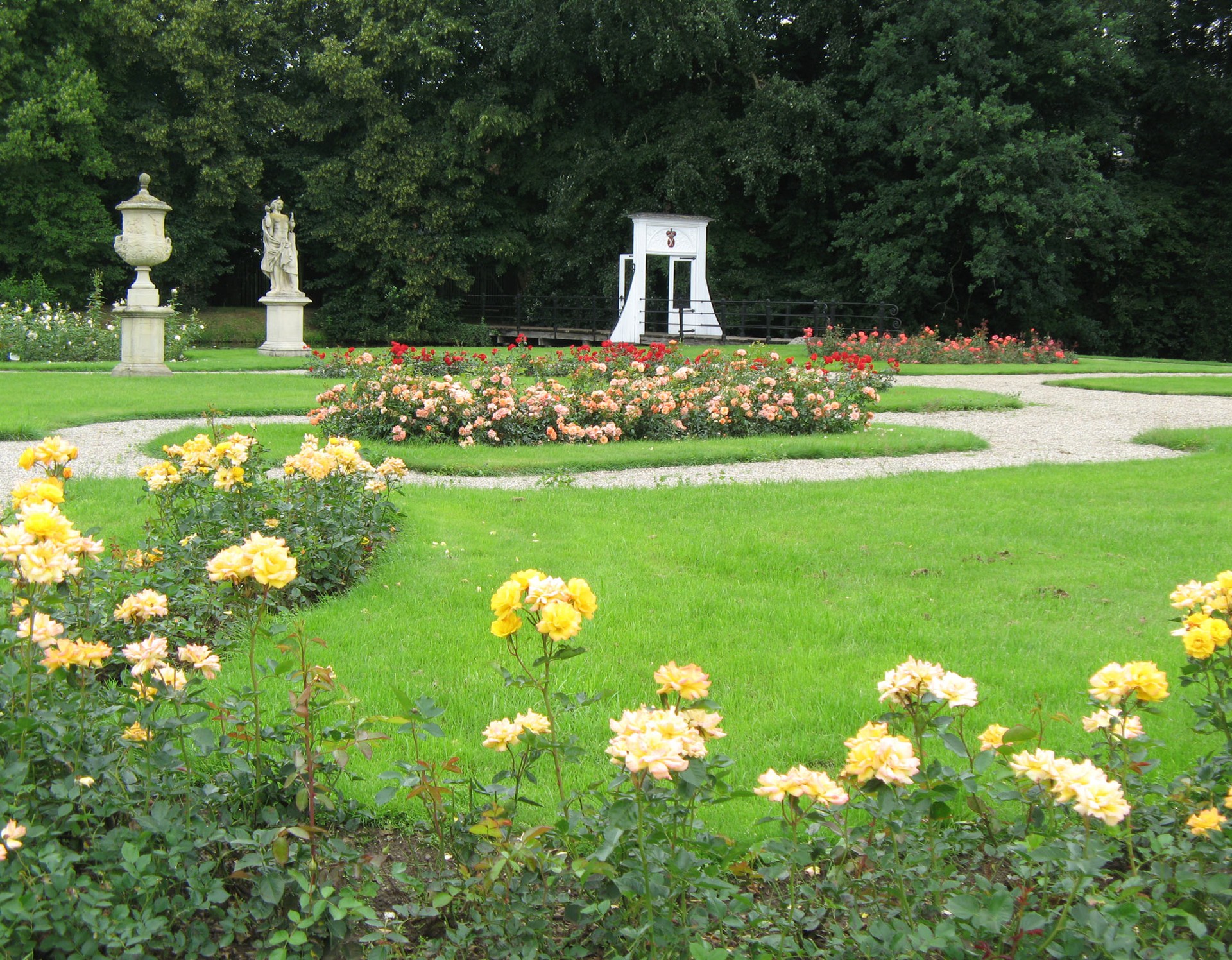 Der Barockgarten an der Wasserburg Anholt. Verziert wird der Garten durch verschiedenfarbige Rosensträucher. Auch zwei von mehreren barocken Skulpturen sind zu sehen.