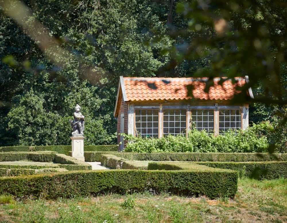 Blick über mehrere Hecken des Gartens am Haus Rüschhaus. Im Hintergrund sieht man eine Skulptur sowie einen Gartenschuppen.