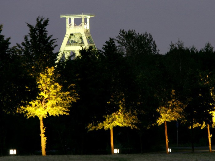 Beleuchteter Bäume sowie der beleuchtete Förderturm des Deutschen Bergbaumuseums in Bochum.