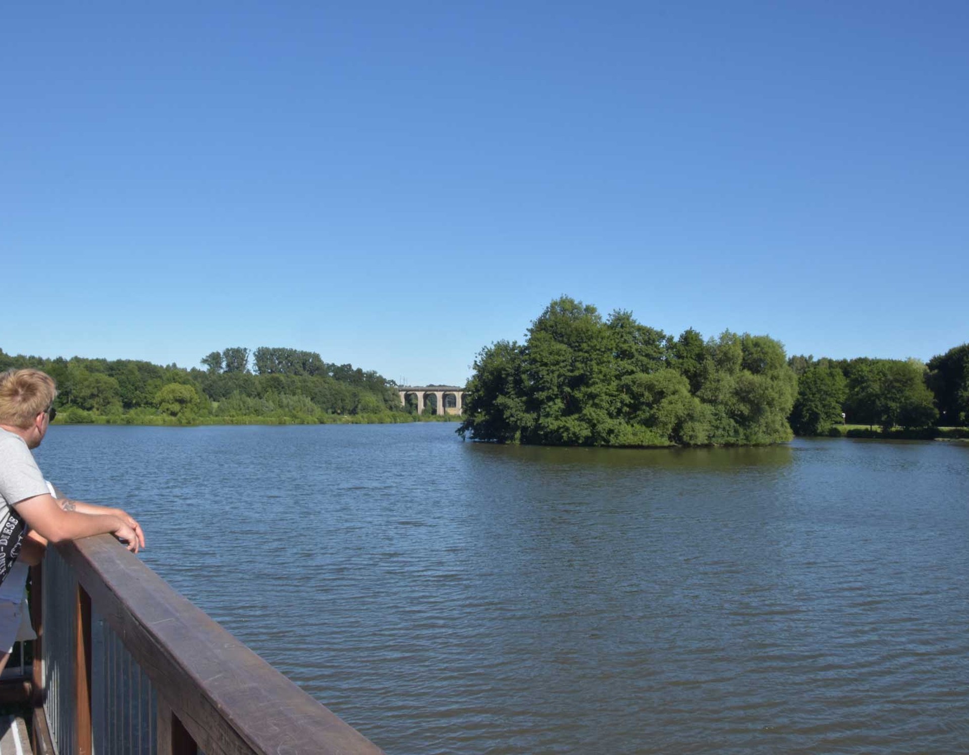 Blick auf den Obersee in Bielefeld von einer Aussichtsplattform. Zu sehen ist eine der Inseln im See. Links davon ist das Schildescher Viadukt sichtbar.