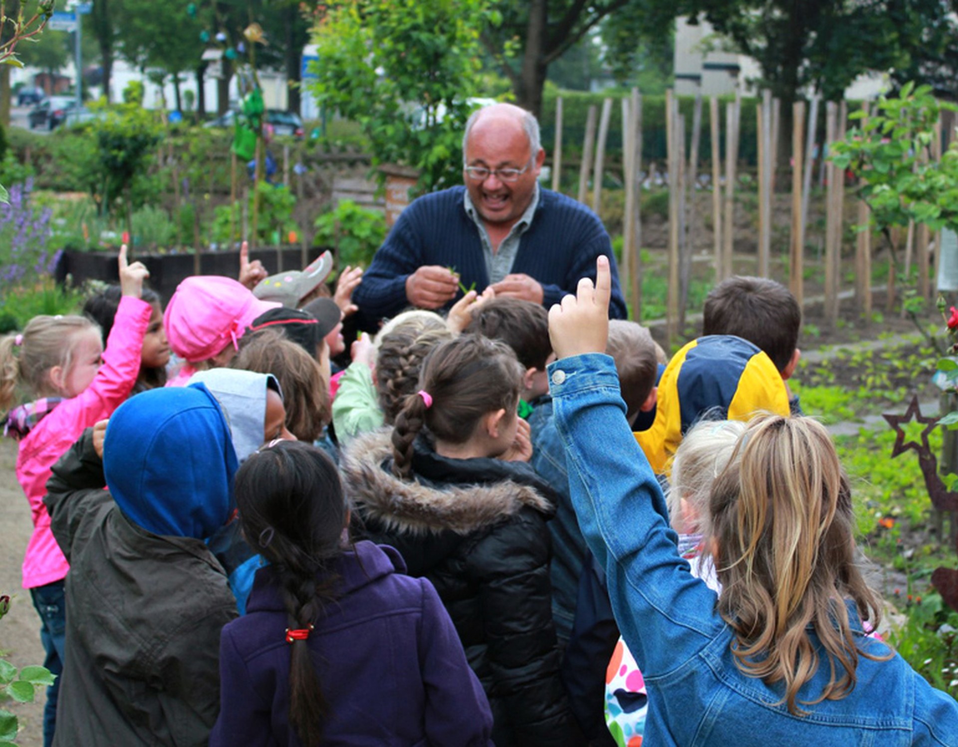 Eine Gartenführung für Kinder im Internationalen Mehrgenerationengarten Lippstadt. Die Gruppe steht an einem der Beete des Gartens.