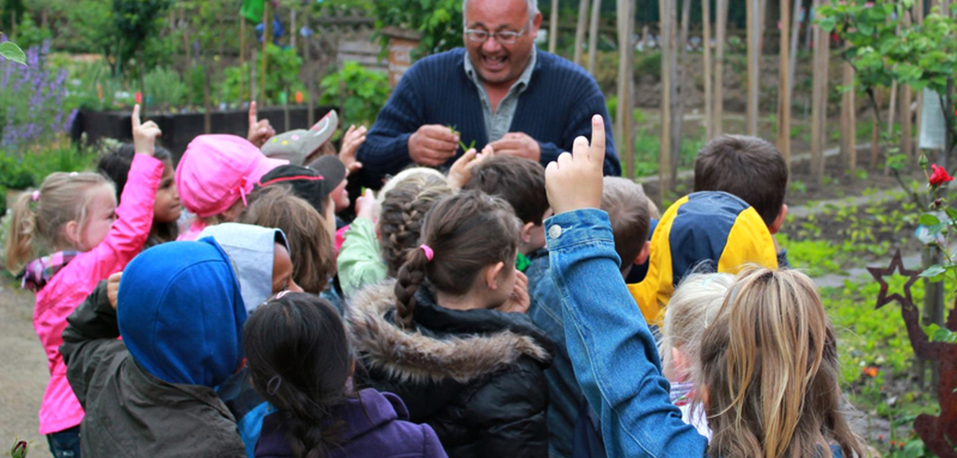 Eine Gartenführung für Kinder im Internationalen Mehrgenerationengarten Lippstadt. Die Gruppe steht an einem der Beete des Gartens.