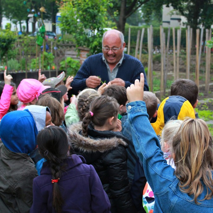 Eine Gartenführung für Kinder im Internationalen Mehrgenerationengarten Lippstadt. Die Gruppe steht an einem der Beete des Gartens. (öffnet vergrößerte Bildansicht)