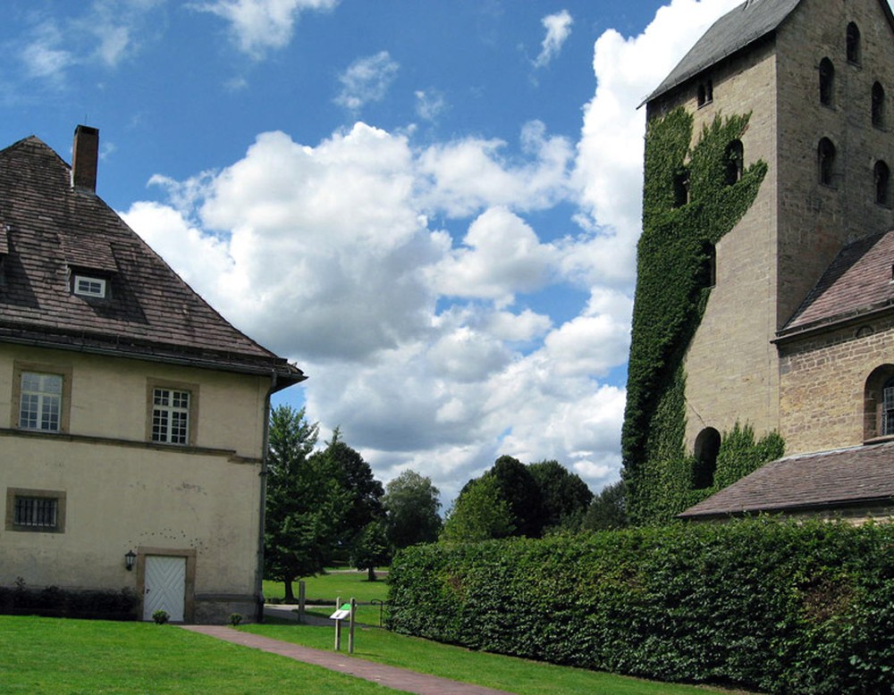 Zwischen dem Nordflügel des Schlosses Gehrden und der Kirche St. Peter und Paul sieht man einen Teil des Schlossparks.